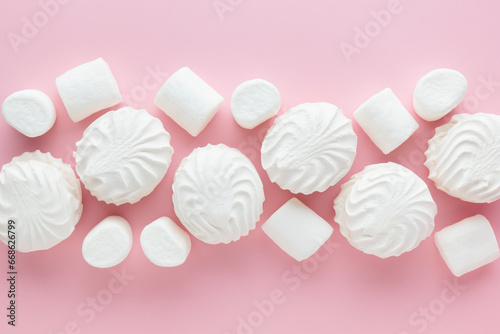 White marshmallows and zephyr on light pastel pink table. Banner with empty space for the text