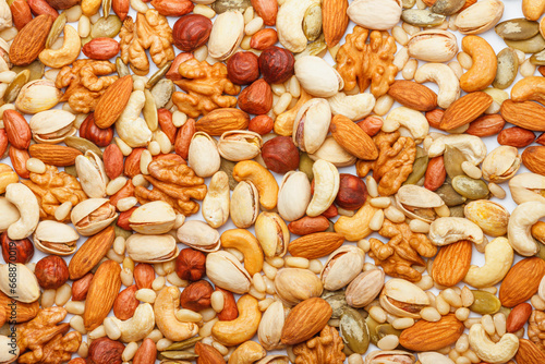 Background from different types of nuts and seeds - peeled walnut, hazelnuts, peeled peanut, pine nut kernels, almond seeds, cashew seeds, pistachio nuts in the shell, pumpkin seeds