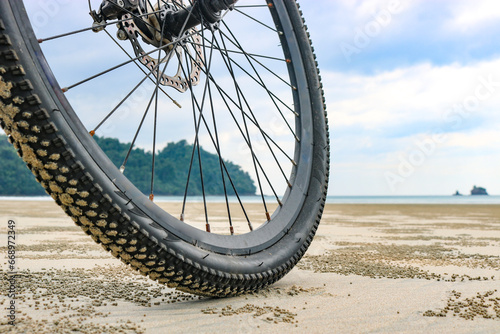 Low angle of a bicycle wheel on the beach, on the sea sand at low tide. The concept of cycling in unusual places.