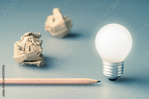 Glowing light bulb with pencil and crumpled paper balls, inspiration, start writing, writing tips
