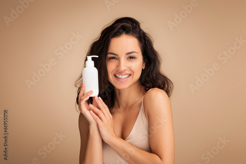 Pretty brunette lady holding bottle with beauty product