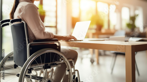 copy space, stockphoto, Woman in a wheelchair working on a laptop in an office, handicap and disability. Disabled woman working with a laptop in an office environment.