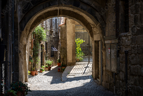a narrow cobbled street with typical architecture in the medieval old town of Viterbo, Lazio, Italy