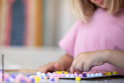 A child makes a craft using a multicolored pompom close-up. Children's leisure, development and preschool education.