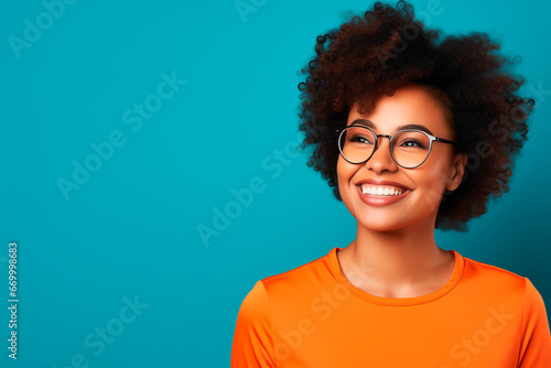  a young afroamerican woman with glasses wear a orange top on blue background