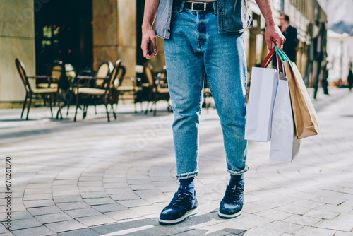 Hipster guy in denim wear walking near stores in mall