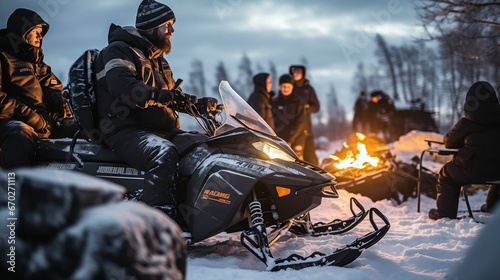 Snowmobilers gathered around a warming campfire