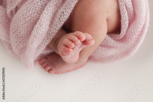 Close-up of tiny, cute, bare toes, heels and feet of a newborn girl, boy. Baby foot on pink soft coverlet, blanket. Detail of a newborn baby legs. Macro horizontal professional studio photo. 