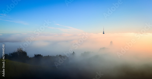 Auckland Sky Tower above a sea of fog. View from Mt Eden summit with the volcanic crater in foreground. Auckland.