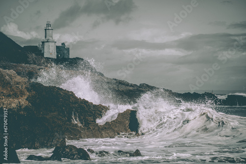 Immerse yourself in the dramatic beauty of Mumbles Lighthouse, where powerful waves crash against the rocks below. The muted colors intensify the somber mood, creating a striking composition capturing