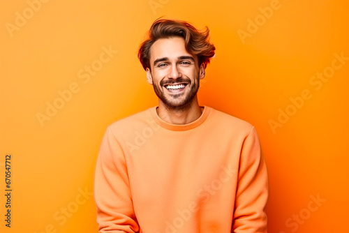 Homme sympathique avec une barbe posant avec un pull orange sur un fond orange