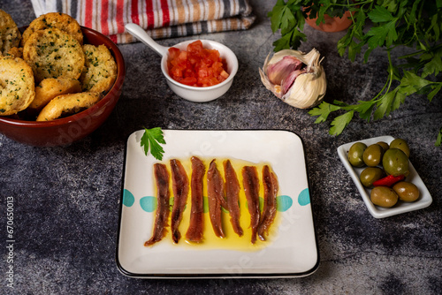 Cantabrian anchovies in olive oil and along with some toast with parsley, chopped tomato, garlic and olives, Spanish tapa.