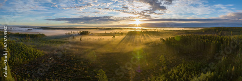 Scenic drone panorama photo of very foggy sunrise over forest, landscape in North Sweden, golden sun light beams and shadows. Beautiful northern Sweden, Vasterbotten, Umea, lens flare