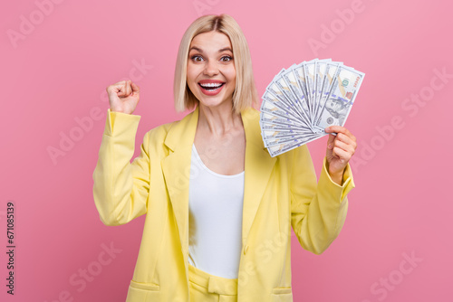 Photo of funky lucky lady wear yellow jacket suit rising fist holding cash fan isolated pink color background