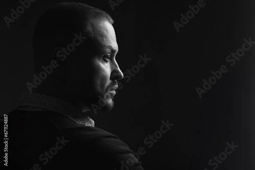 Fabulous at any age. Profile portrait of charismatic 40-year-old man posing over black background. Short haircut. Classic, smart casual style. Close up. Copy-space. Black and white studio shot