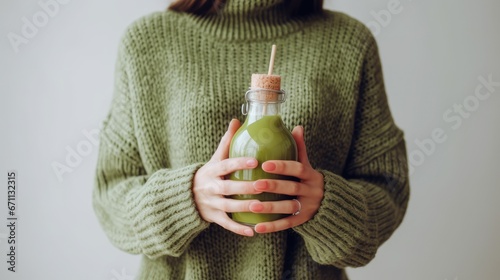 Winter seasonal smoothie drink detox. Female in woolen sweater holding bottle of green smoothie or juice making heart shape with her hands. Clean eating, weight loss, healthy dieting food concept 