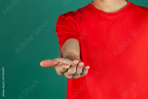 Chico vestido de papa noel en navidad mostrando con sus manos. hombre de rojo y blanco sobre fondo verde