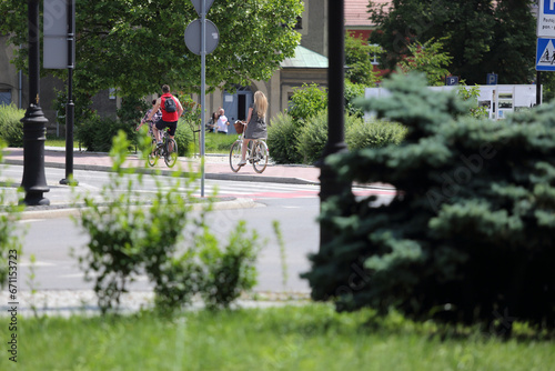 Kobieta i mężczyzna jadą na rowerach chodnikiem w mieście.