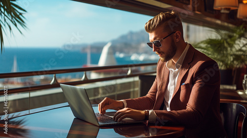 hombre apuesto trabajando en su laptop con vista al mar dentro de un crucero 