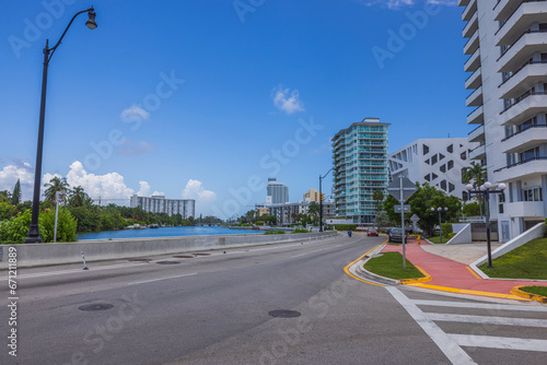 Beautiful view of one of streets in Miami Beach with houses alongside highway and water body, set against backdrop of blue sky with white clouds. USA.