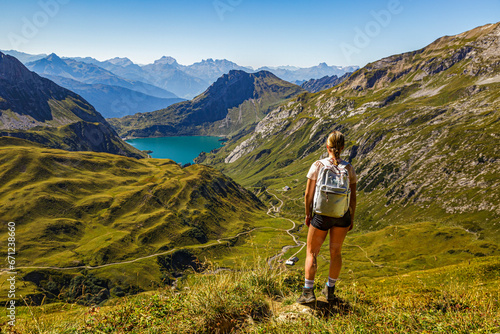 eine junge Frau steht an einem Wanderweg auf einem Berg und schaut auf den Spullersee in Vorarlberg Lech Östereich