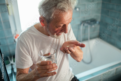 Senior man taking his medication in the bathroom at home