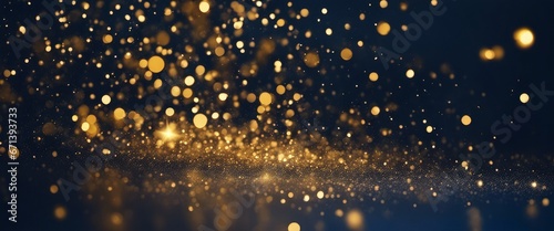 Close up of gold glitter particles on a dark blue background. The particles are different sizes and shapes and they sparkle in the light. The image creates a festive and glamorous mood.