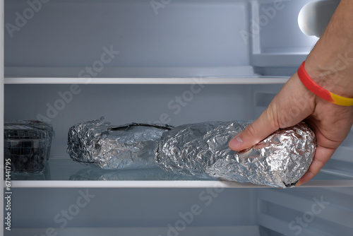 Domowa kanapka zawinięta w folię aluminiową odkładana na półkę w lodówce 