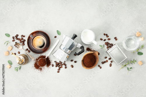 Moka pot, espresso cup, ground coffee, milk, sugar and coffee beans on a grey concrete background