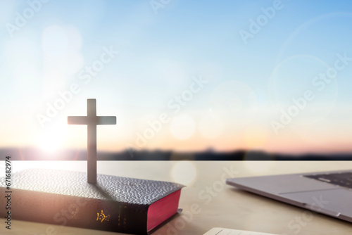 Silhouette wooden cross on holy bible sunrise background