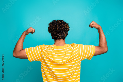 Rear behind portrait of sportive masculine person arms showing flexing biceps isolated on cyan color background