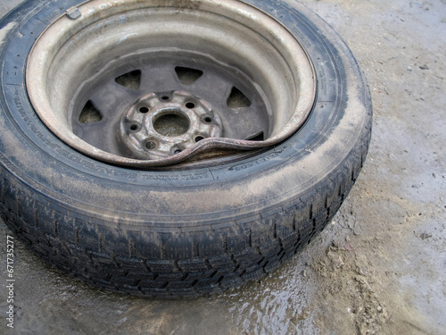 Bent steel rim on a wheel with winter tires. Damaged steel. Wheel with bent steel rim. Car problems, bad roads, financial expenses