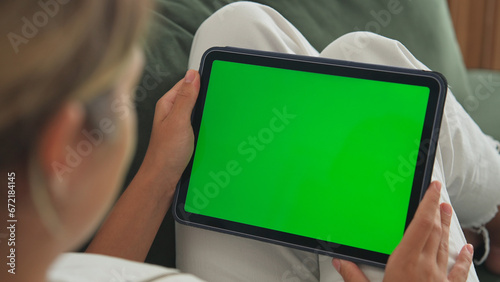 Girl click green screen. Hand hold horizontal ipad close up. Finger tap center tablet. View web store site. One touch chroma key pad. Woman poke display. Person work home room lie sofa. Social media.