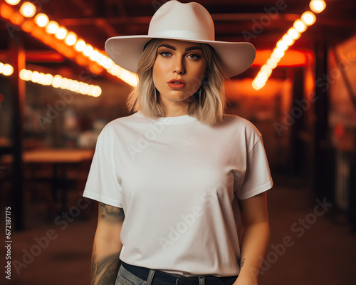 tshirt mock up cowgirl: A woman wearing a white tshirt mockup blank template. Styling is western cowboy, she wears a cowboy hat and is at a bar, club