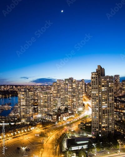 Moon in a blue dusk sky over traffic light trails on Pacific Blvd and False Creek. Vancouver British Columbia