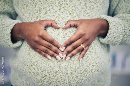 Pregnancy, closeup and woman with a heart shape on her maternal belly for care and motherhood. Health, zoom and African pregnant female person hands on stomach with a love sign or emoji for her baby.