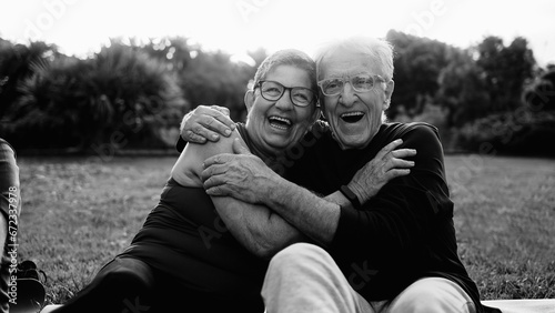Happy senior couple having fun smiling in Park City. Older people enjoy together outdoors in nature. Black and white editing