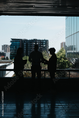 Silhouette of three business partners working remotely in urban city area, planning projects, discussing paperwork and sharing business ideas
