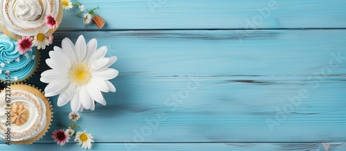 Buttercream topped cupcake Tasty cake with frosting and a miniature chocolate bar Sweet treat with a topping Placed on a rustic wooden background Decorated with gerbera flowers Scrumptious m