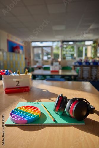 Ear Defenders Or Headphones And Fidget Toy To Help Child With ASD Or Autism On Table In School Classroom