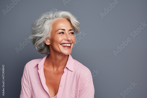 Beautiful gorgeous 50s mid age beautiful elderly senior model woman with grey hair laughing and smiling. Mature old lady close up portrait. Healthy face skin care beauty, skincare cosmetics, dental. 