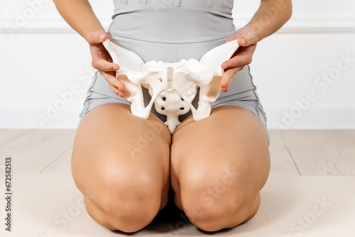 Close-up of the female pelvis in the hands of an athletic, healthy woman. Gynecology, women's healthcare and medicine and healthy body concept.