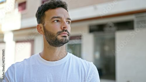 Young hispanic man looking to the side with serious expression at street