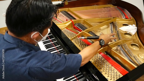 Asian man repairing the piano in a concert hall