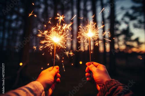 two hands holding sparklers against the background of a night forest reflecting the onset of Christmas