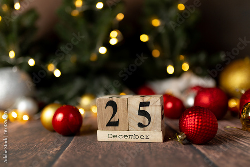 Old vintage wooden calendar for the date of Christmas December 25 against the background of New Year's lights of garlands of bokeh light bulbs