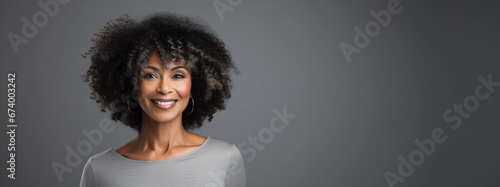 Happy beautiful african american ethnicity woman in 40s on dark gray background with copy space.