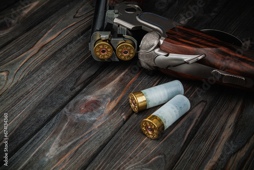 Classic trigger double-barreled hunting rifle on a wooden background. Concept postcards for hunters. Smooth-bore hunting rifle open for reloading.