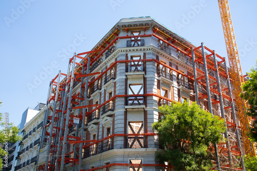 Madrid, Spain. May 9, 2022. Restoration construction of an old apartment building, house facade. Renovation of vintage property. Construction site with metal scaffolding Exterior windows without glass