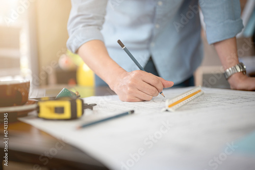 Close up architect and engineer working on renovation or building project writing and drawing on floor plan blueprint with instrument ruler equipments designing layout in agency office workplace